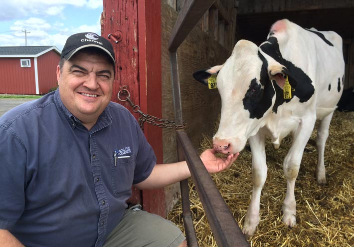 Jeff King of Kings-Ransom Farm squatting down next to one of his dairy cows 